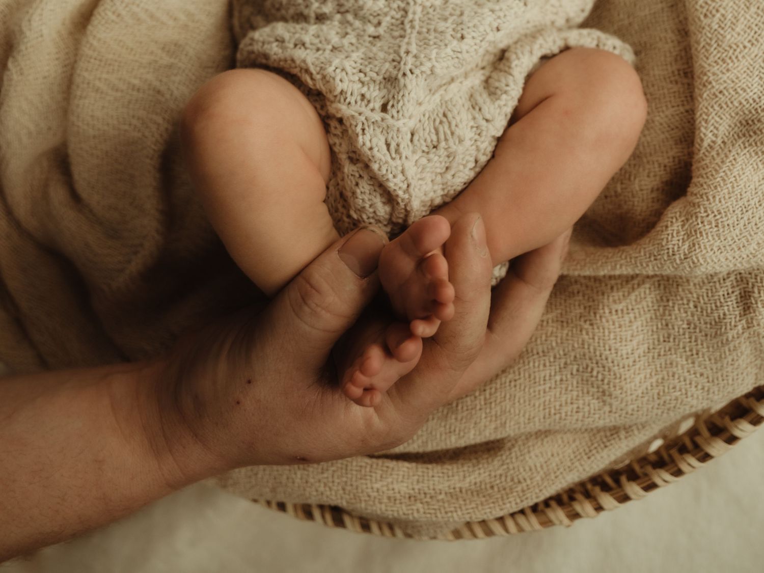 Newborn feet held in father's hand. Image by dmcgphoto.