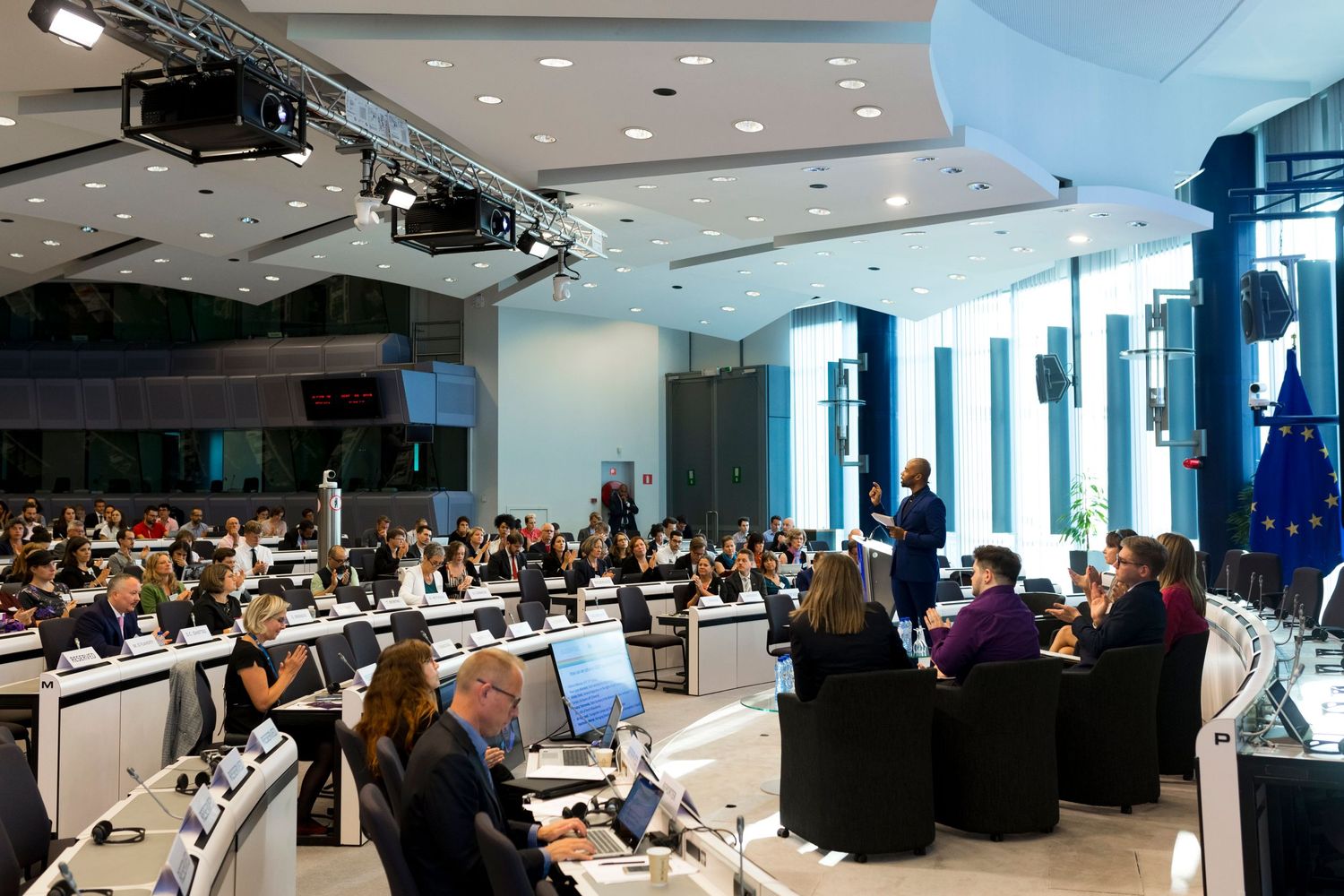 Large conference room filled with attendees at workstations during a business event.