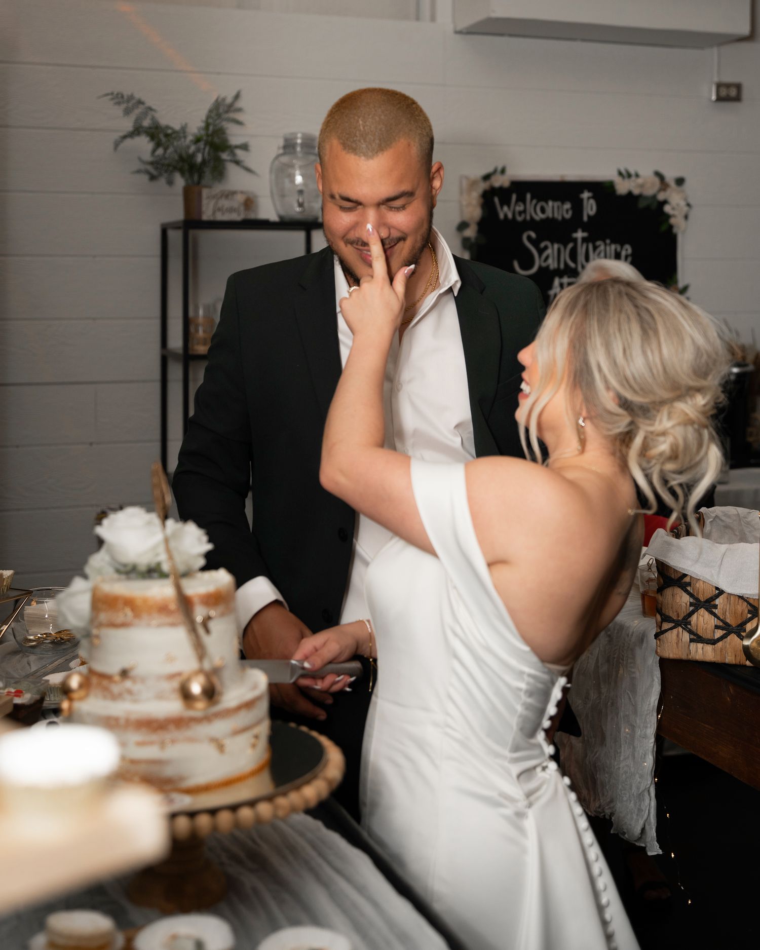 Bride and groom cake cutting with bride rubbing icing on the grooms nose