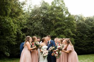 Wedding celebration on a lush green lawn with trees in the background.