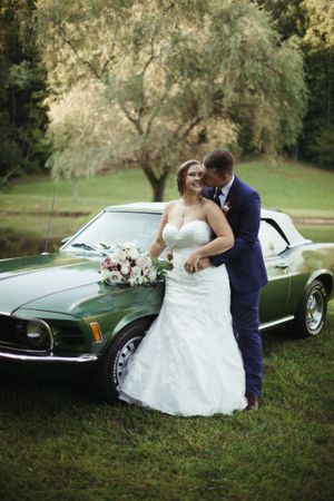 A couple poses with a classic green Mustang car during their wedding photoshoot.