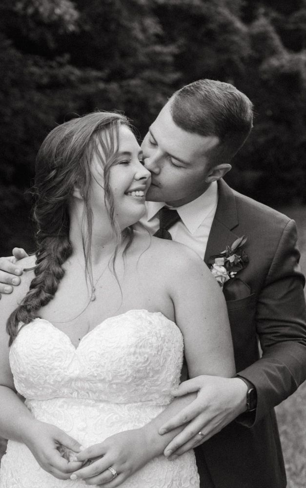 An intimate black and white portrait captures a tender moment between newlyweds.