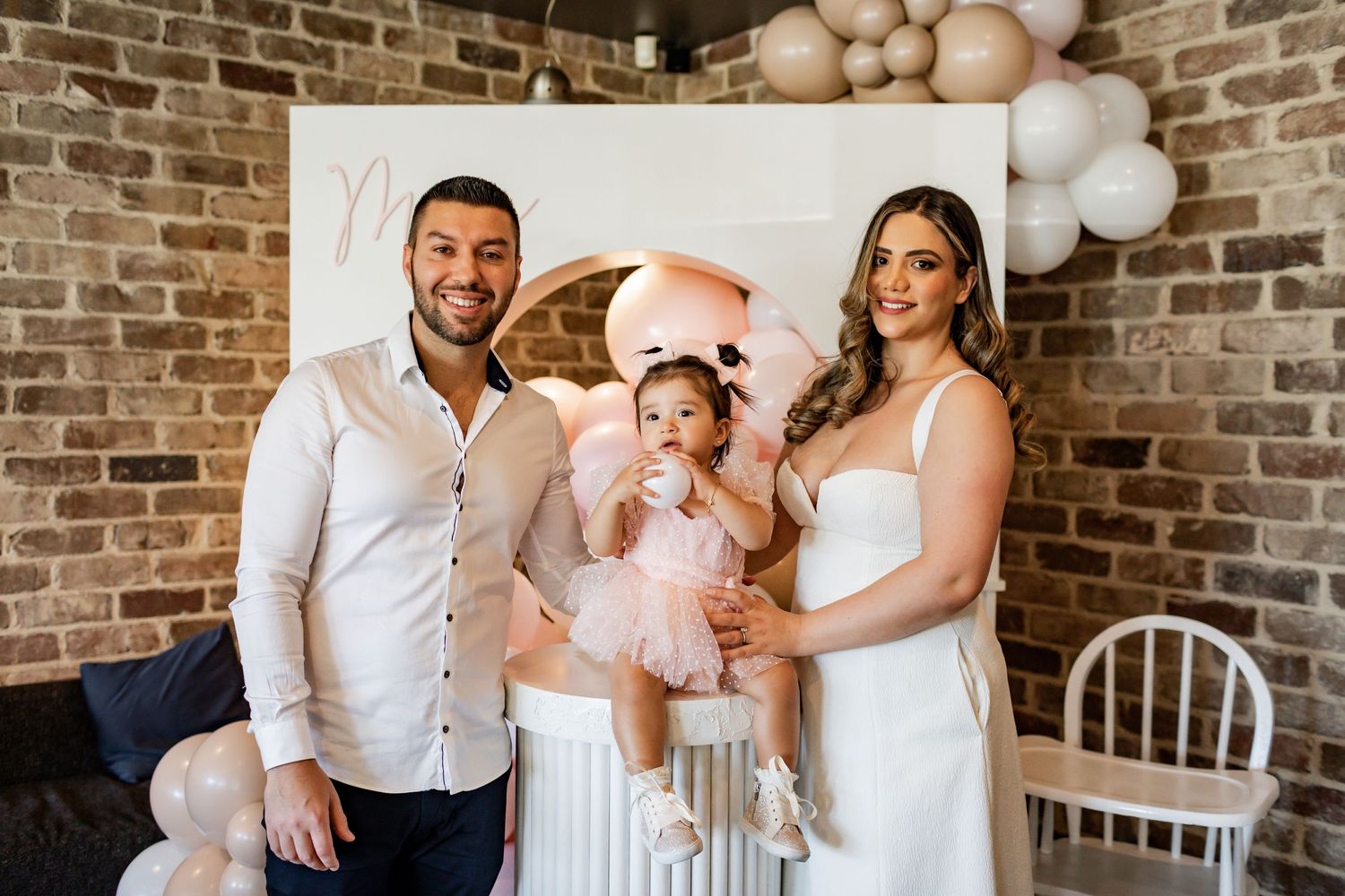 Candid family moment captured at a celebration with elegant balloon and floral decorations.