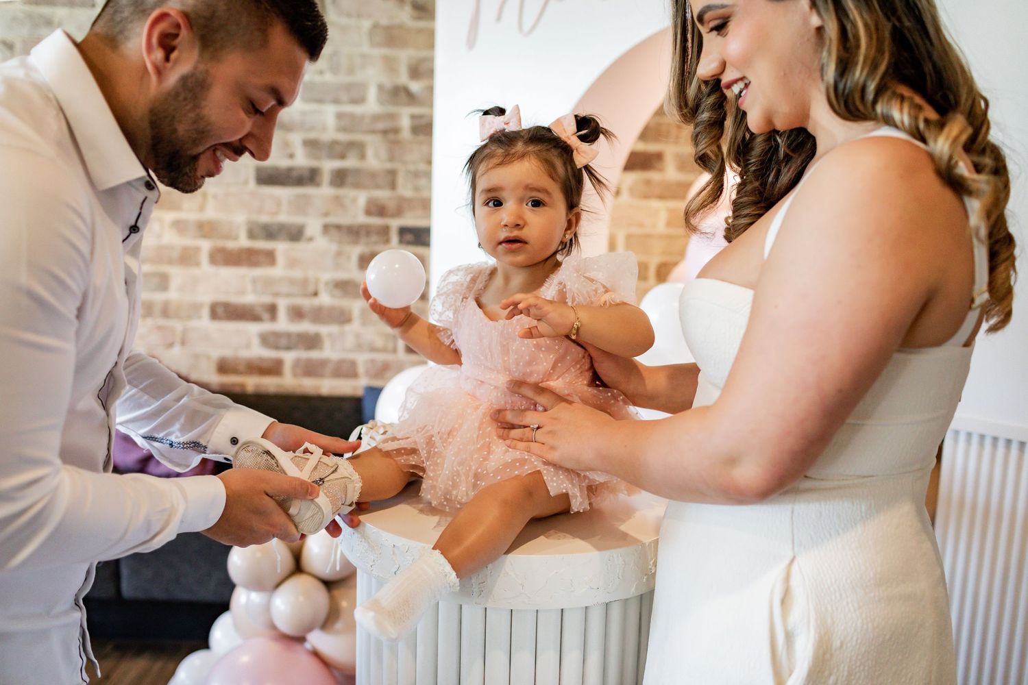 A special moment captured during a celebration with pink tulle and balloons in the background.