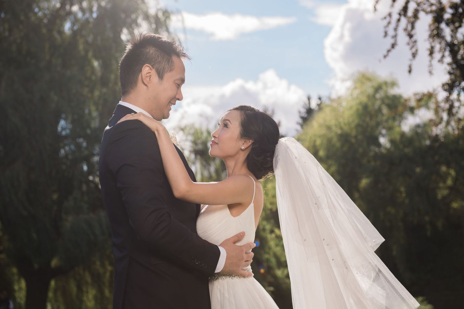 A tender moment between newlyweds backlit by soft sunlight.