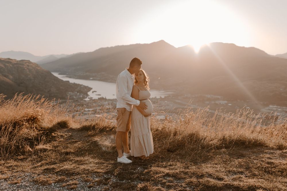 Romantic sunset portraits captured on hillside overlooking coastal landscape.