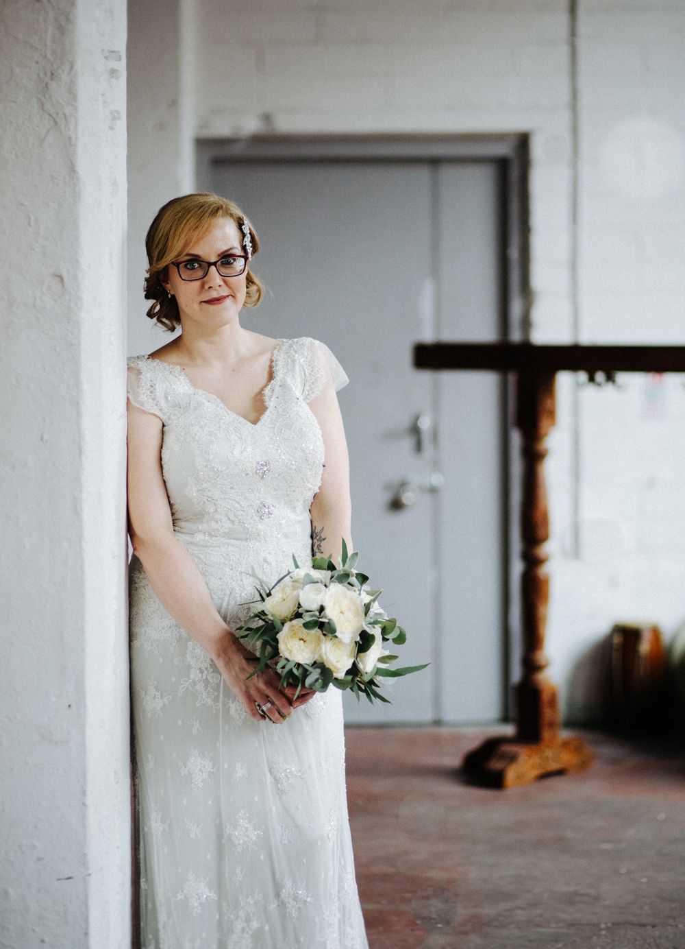 A bridal portrait featuring a lace wedding dress and white floral bouquet.