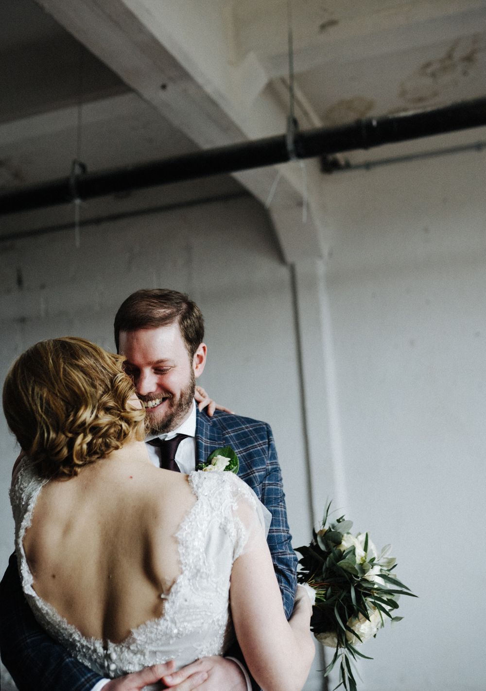 Intimate moment between couple in formal attire sharing an embrace in an industrial space.