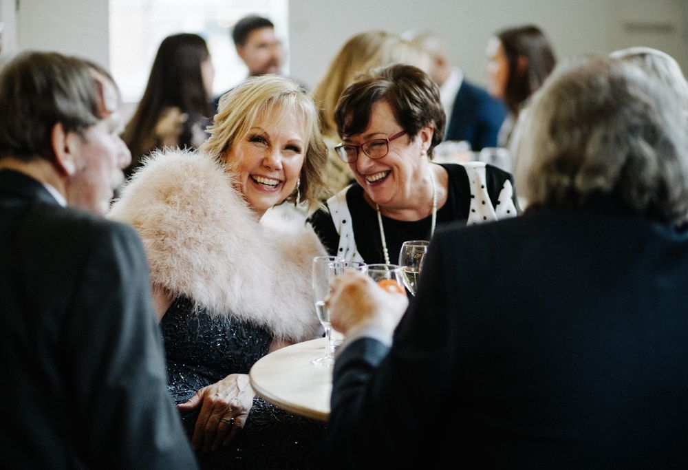 A lively group of wedding guests engaged in animated conversation at a reception table.