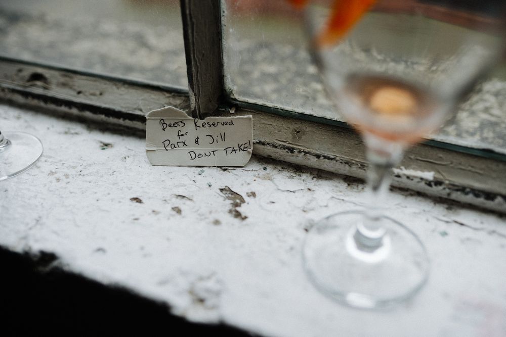 Close-up of a handwritten note near a wine glass on a weathered windowsill.