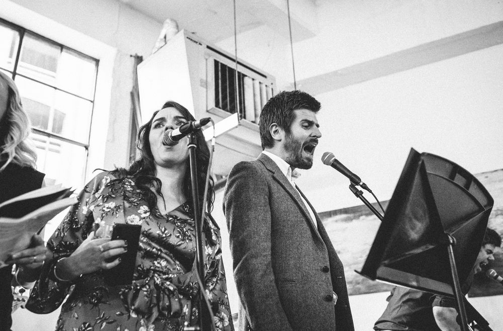 Black and white photo of people singing karaoke with enthusiasm at a celebration.