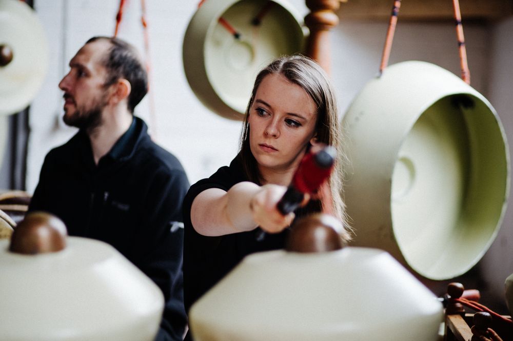 Musicians adjusting large lamp-like instruments during event setup.