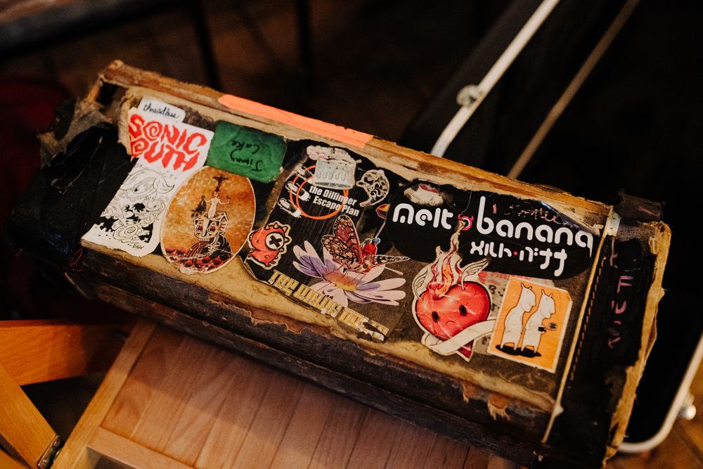 A vintage-style music case covered in colorful stickers and band logos.