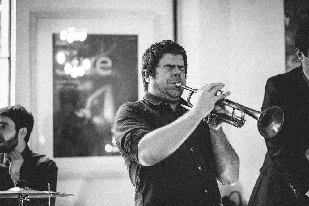 A musician plays trumpet passionately during a live performance.