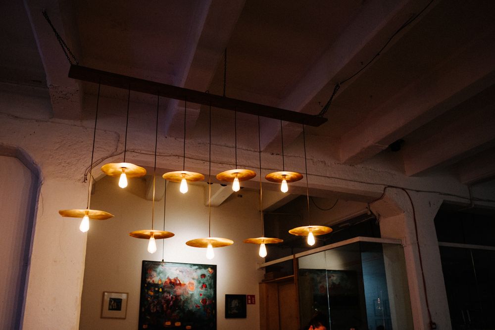 Modern pendant lights illuminate a dark room with exposed ceiling beams.
