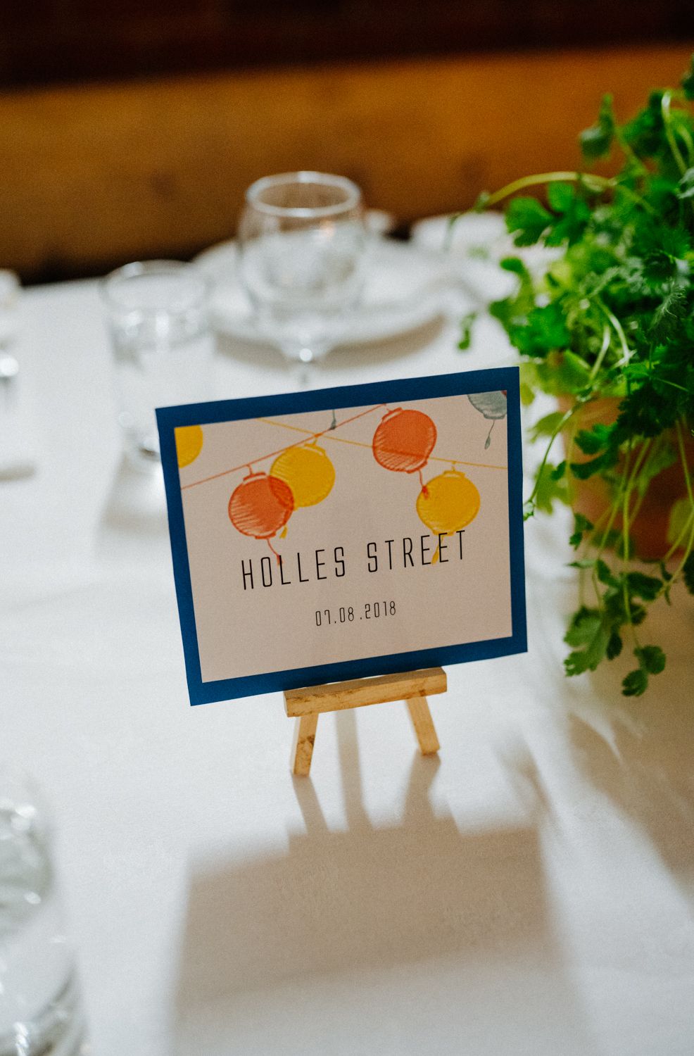 Table place card with citrus illustration reading 'Holles Street' on small easel stand.