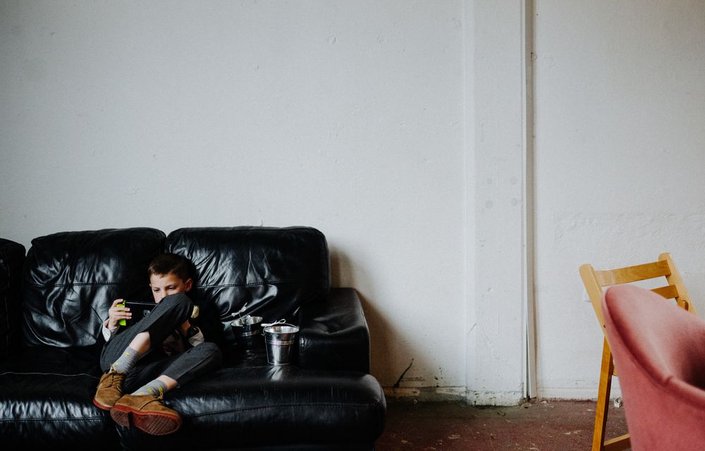 Person sitting alone on black leather couch in minimalist room setting.