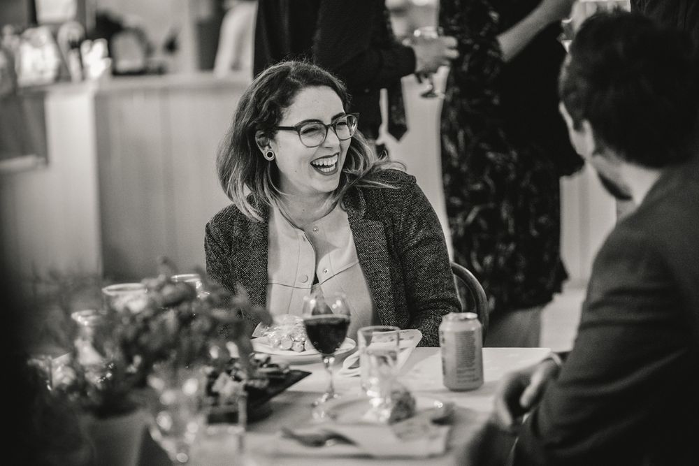 Candid moment of dinner conversation at restaurant table with wine glasses and flowers.