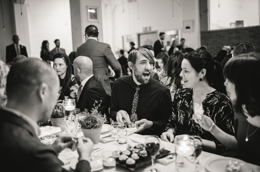 Guests share laughter and conversation around a formal dinner table at an elegant black and white event.