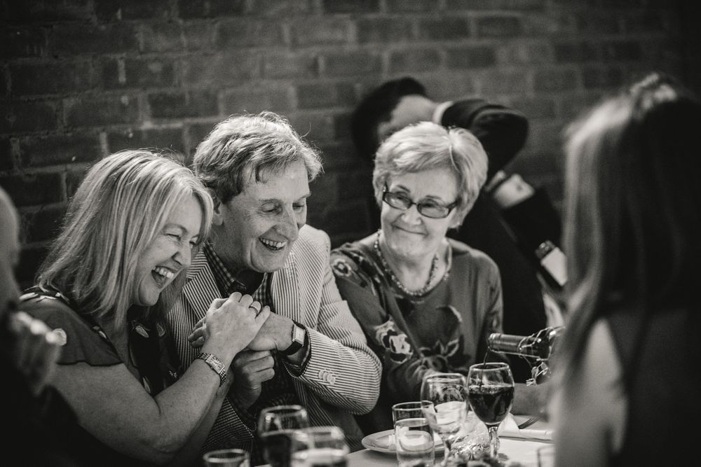 Three women share an entertaining moment while dining together at a social gathering.