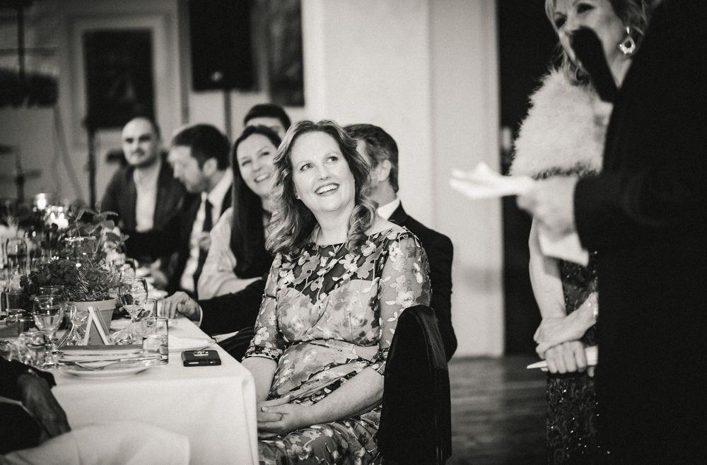 Guest smiling during dinner celebration at elegantly decorated table setting.
