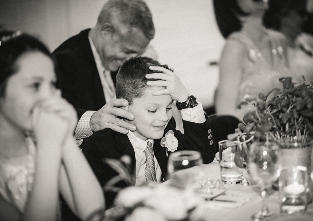 Tender moment captured during formal dinner gathering with elegant table settings.