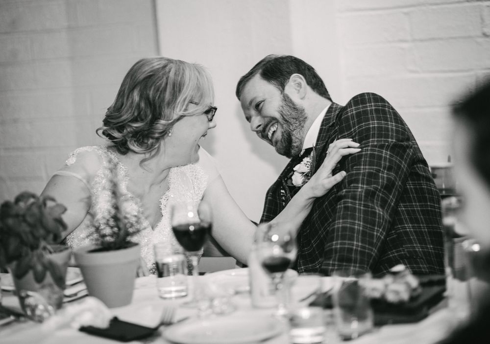 Couple sharing intimate moment of laughter at formal dinner table.