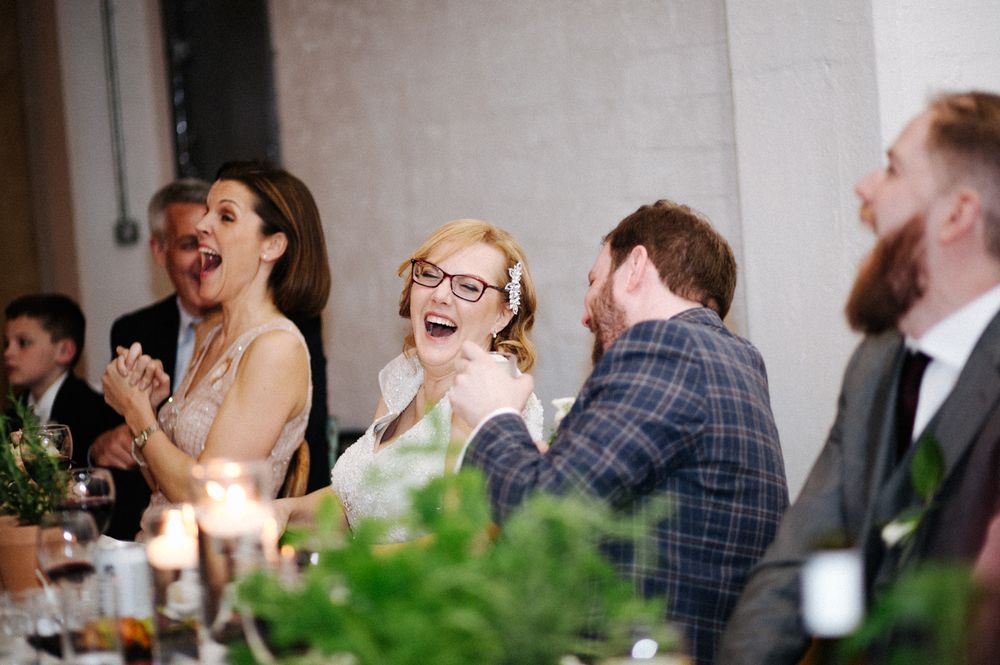 Wedding guests sharing infectious laughter during a reception dinner.