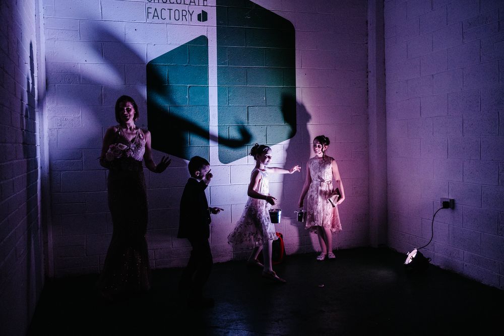 Purple-lit shadows dance on a wall as people gather in a dark room.