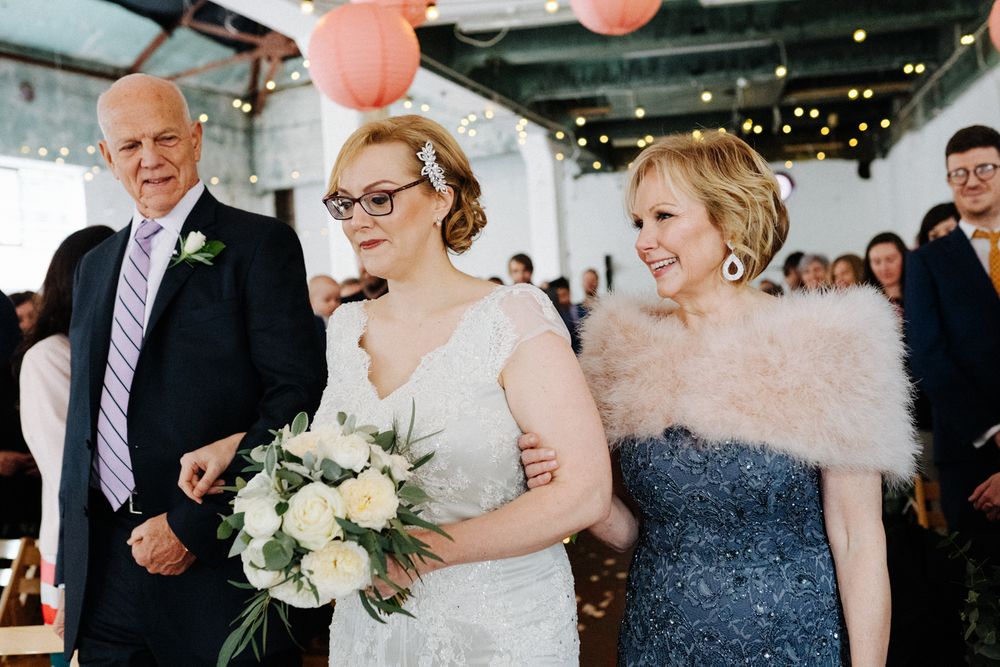 Wedding party members smile and celebrate with bouquets of white flowers.
