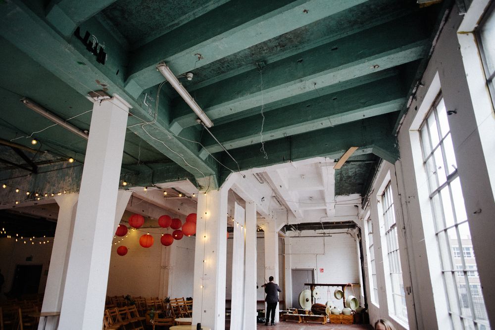 Industrial wedding venue interior with exposed beams, white columns and hanging red paper lanterns.