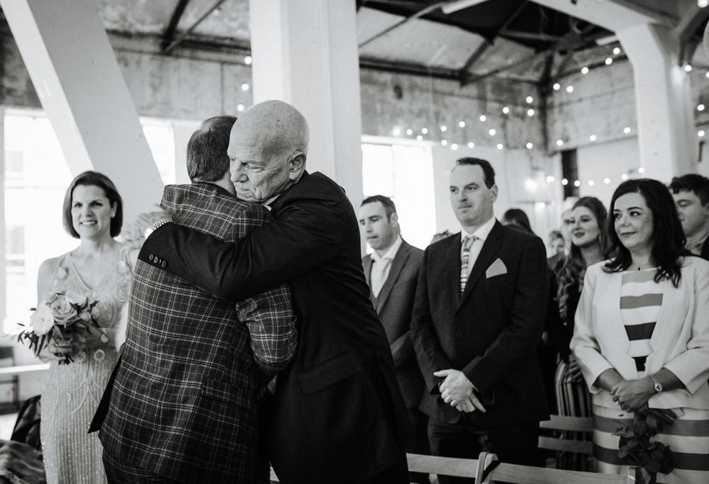 Black and white photo of an emotional embrace during a wedding ceremony.