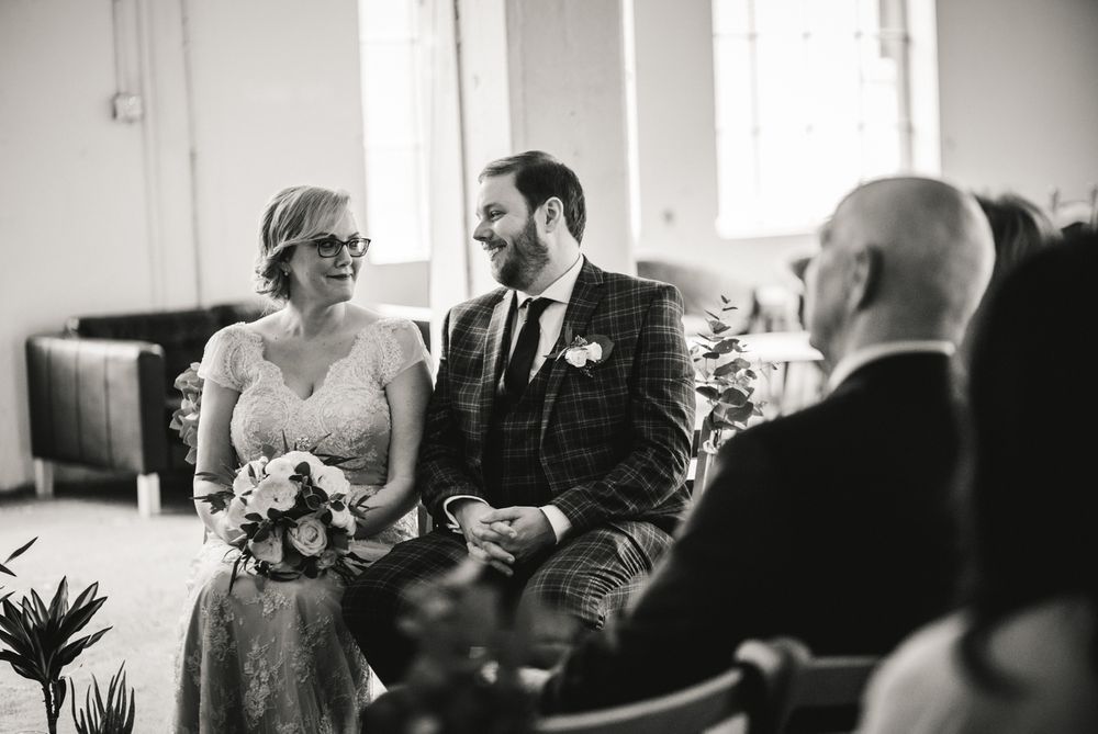 Wedding ceremony participants in elegant attire seated during an intimate indoor gathering.