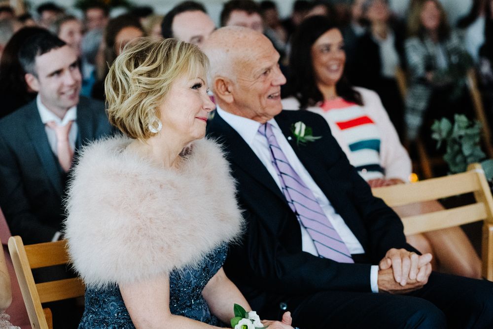 Wedding guests in formal attire sharing a joyful moment during the ceremony.