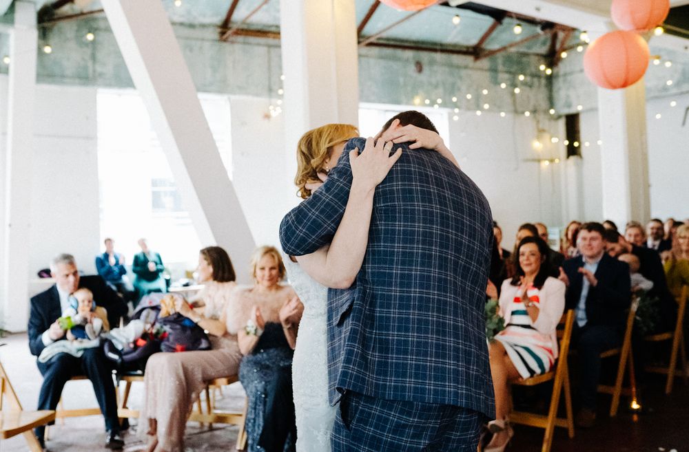 Wedding reception celebration with guests dancing in an airy venue decorated with hanging lanterns.