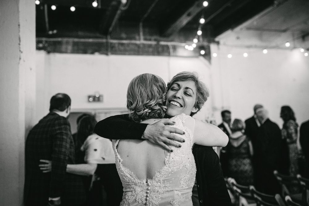 Black and white photo of emotional embrace during wedding celebration.
