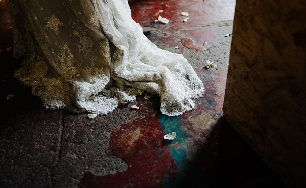 White wedding dress train on red floor with scattered debris and aqua accent.