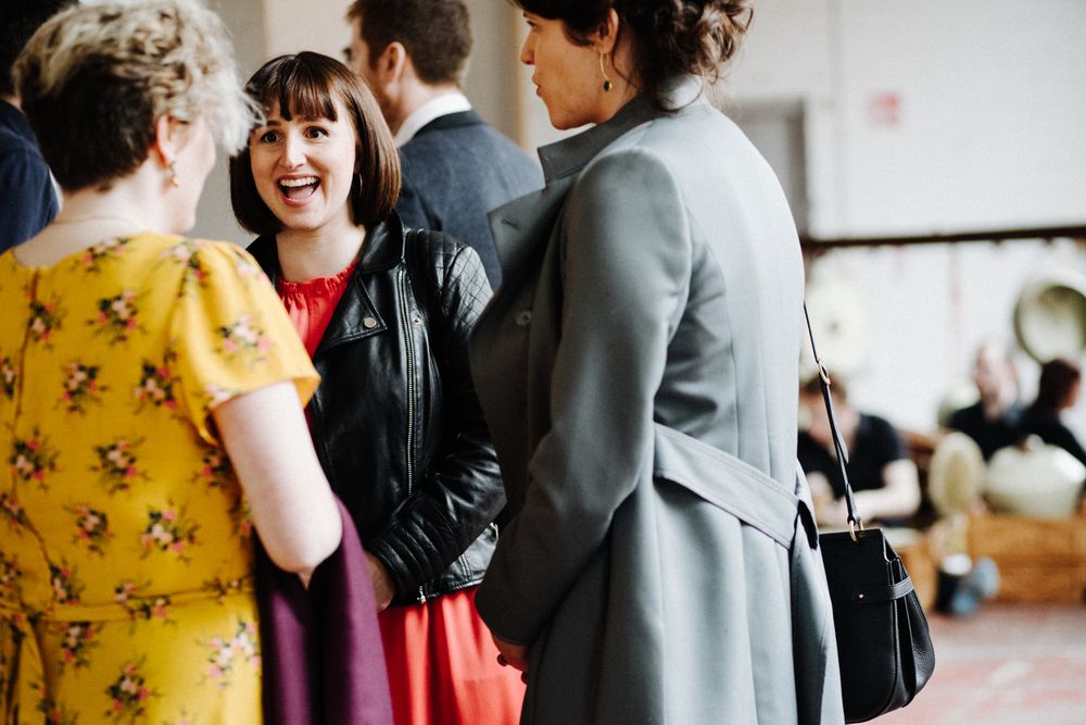 Small group of wedding guests chatting in formal attire.