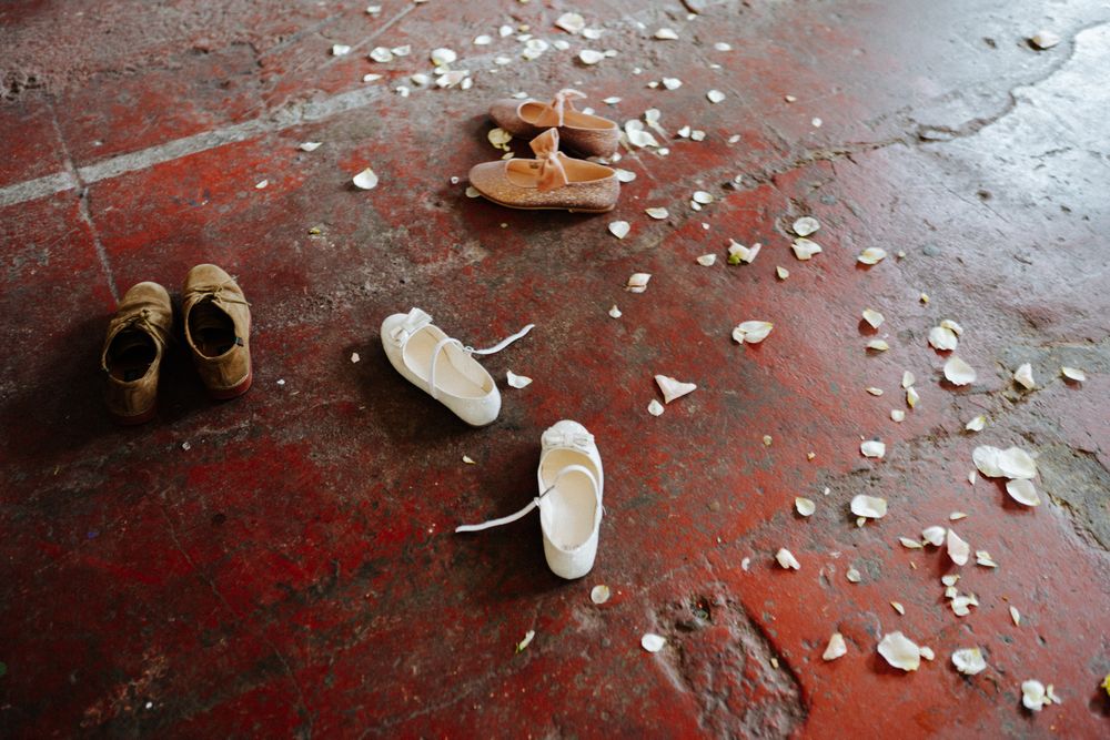 Several pairs of shoes scattered on red floor with white debris.