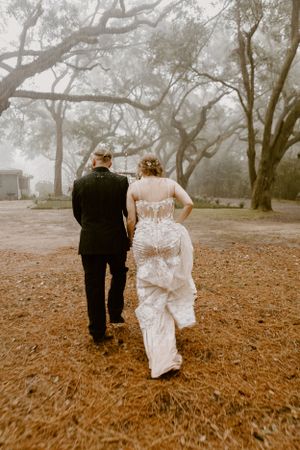 Bride and groom walking through a foggy forest at an enchanted wedding in Mobile, Alabama at the Elizabeth wedding venue