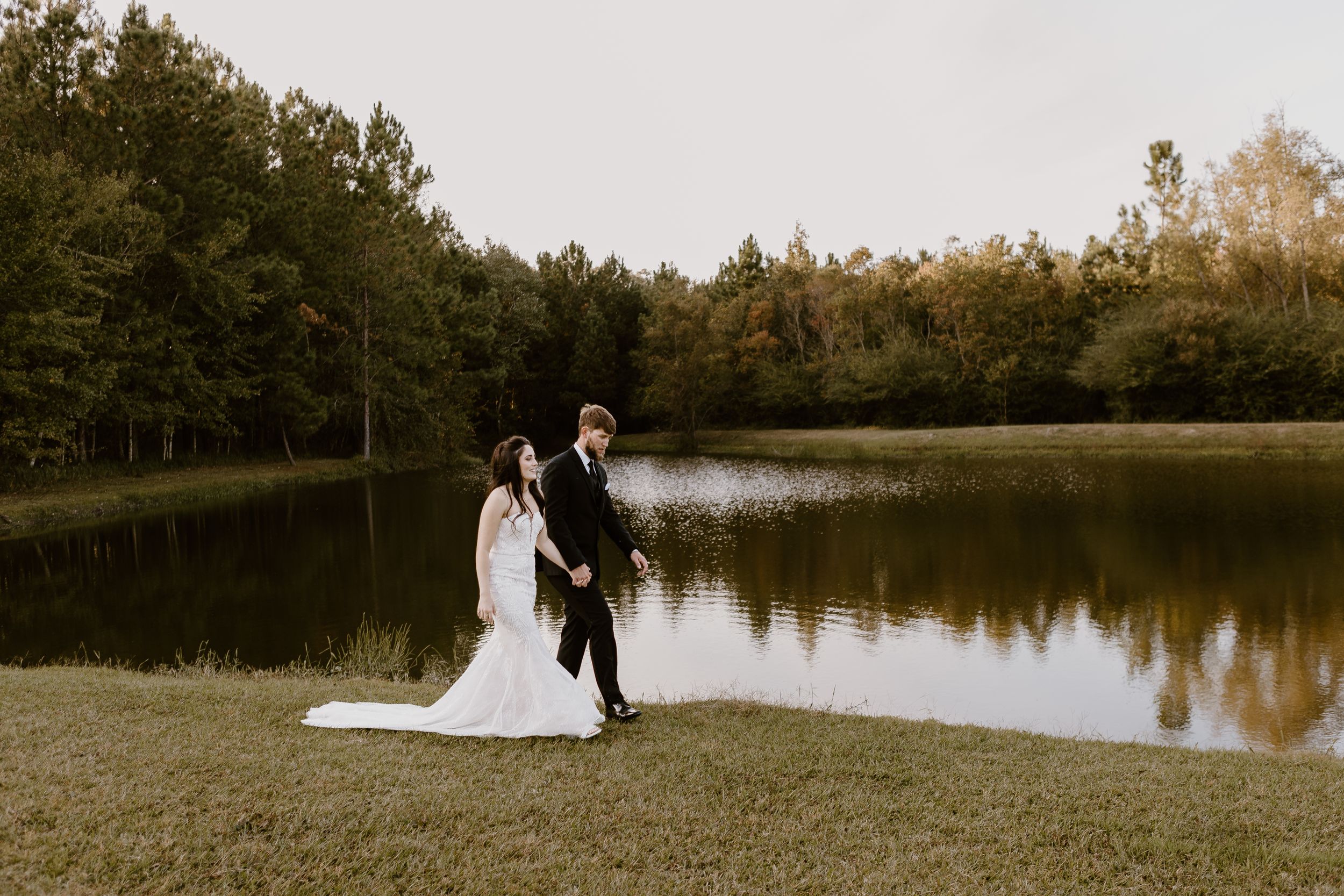 Bride and grooms walking in front of a lake in Mobile, Alabama