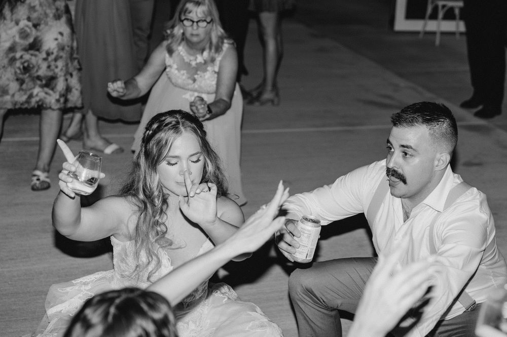 Black and white of bride and groom dancing with drinks in hand