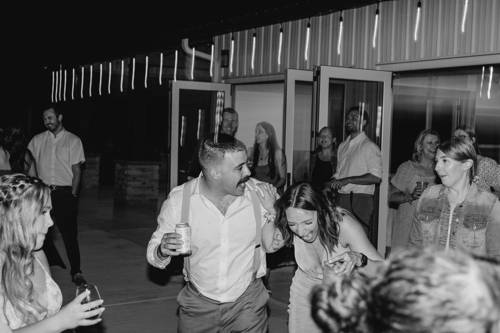 Black and white of Bride and groom arm in arm with friends