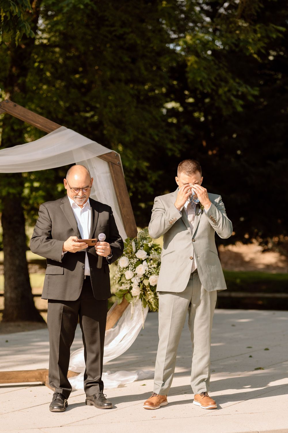 Groom wiping tears from his eyes while standing at end of isle with officiant