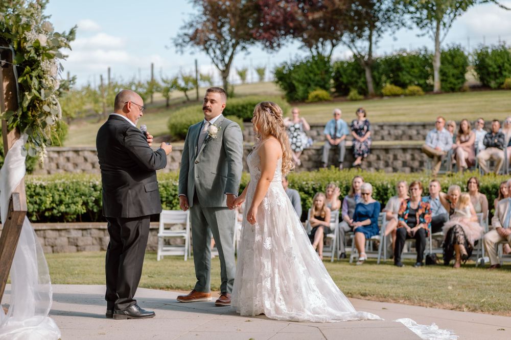 Bride and groom standing at the front of the ceremony with guest in the background