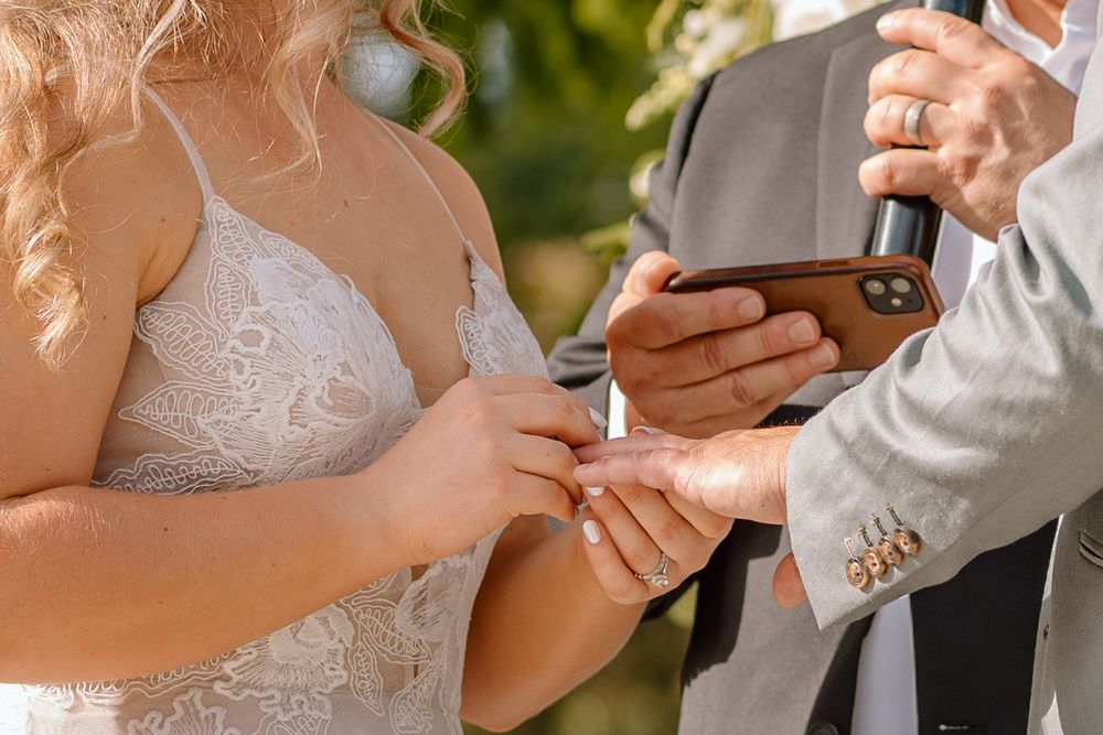 Bride placing grooms wedding band on his hand