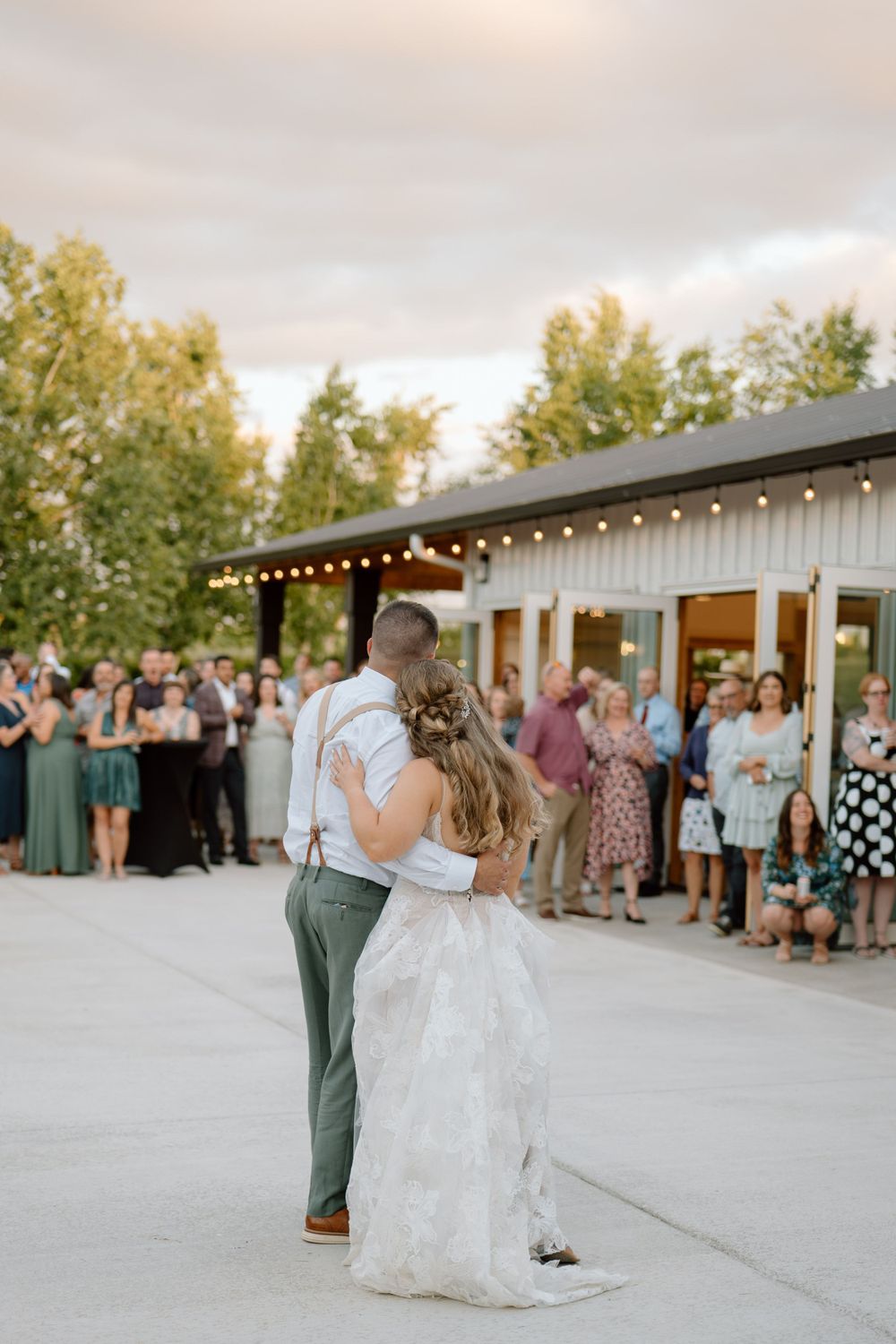Bride and groom slow dancing with guest in the background