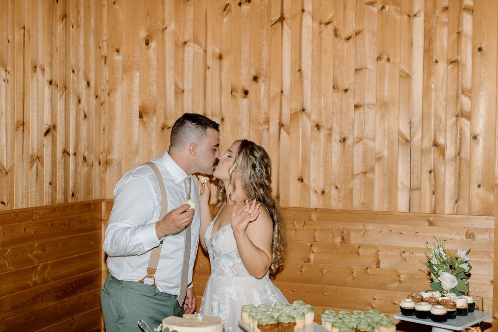 Bride and groom kissing with cupcakes in hand