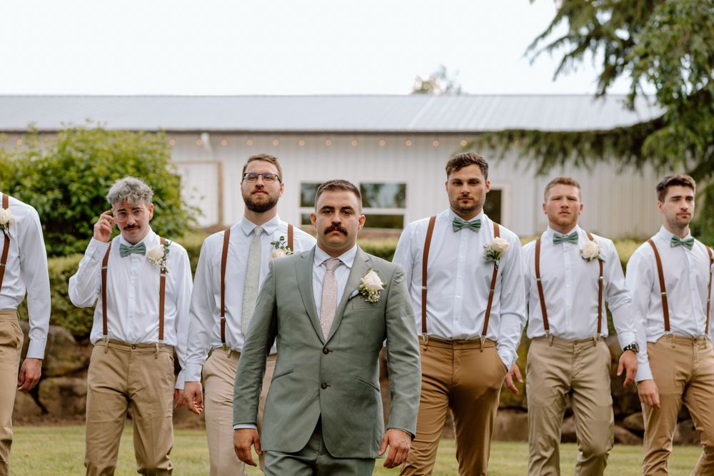 Groom and groomsmen walking towards camera with straight face