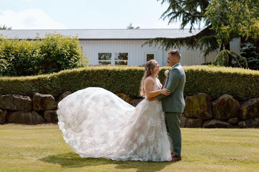 Bride and groom facing each other with brides dress train flowing in the wind